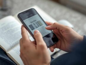 A person is relaxing on a sofa, holding an iPhone that is displaying the Kindle app interface over an open physical book. This image illustrates the process of reading or downloading ebooks on an Apple device. (How Do I Download Kindle Books to iPhone)