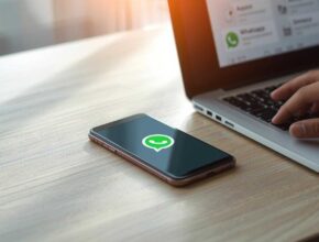 "A realistic smartphone on a desk showing the WhatsApp logo with a laptop nearby, representing WhatsApp APK latest version download process."